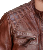 Close-up of a brown leather jacket with quilted shoulder design.
